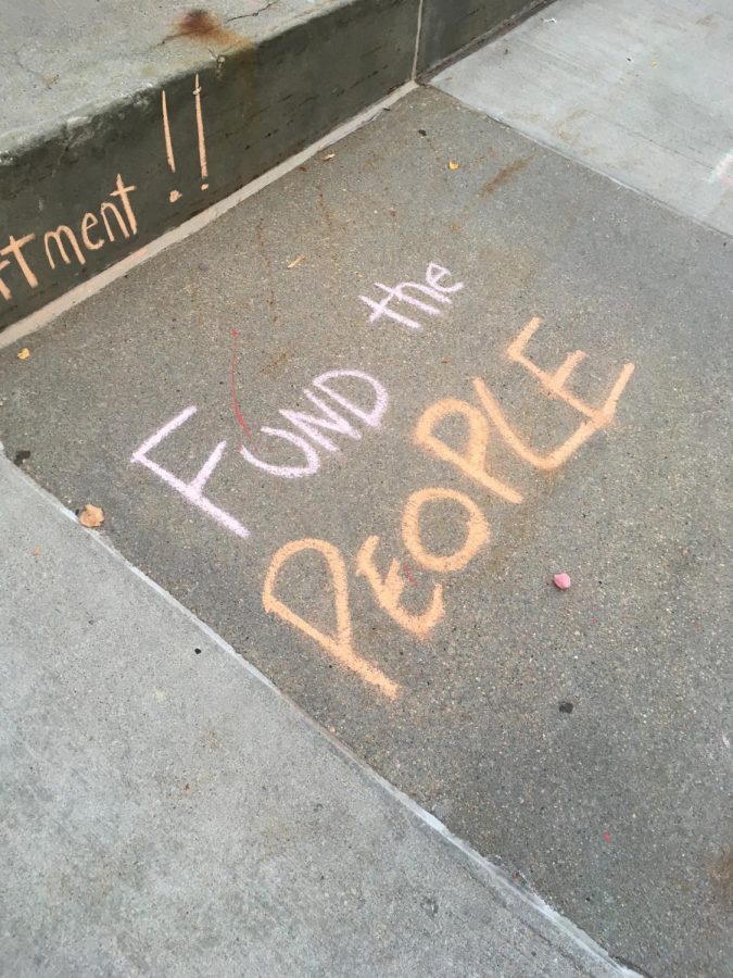 Chalk+outside+city+hall+on+Aug.+3.+Community+organizations+gathered+on+the+plaza+in+protest+while+the+city+budget+hearing+went+on+inside.