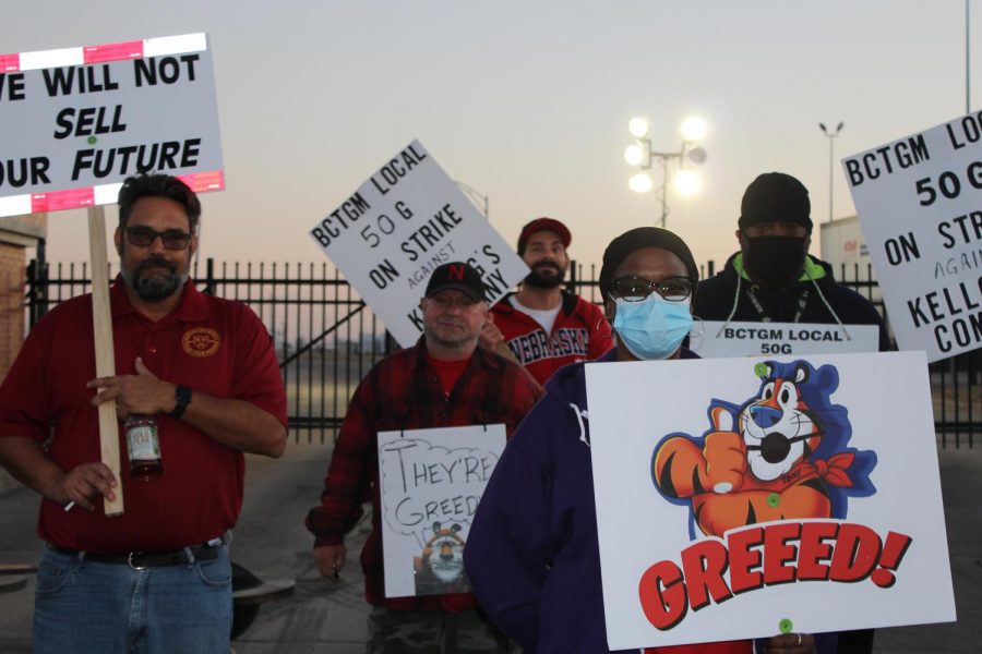 Striking employees stand at the Kelloggss factory gates with protest signs.