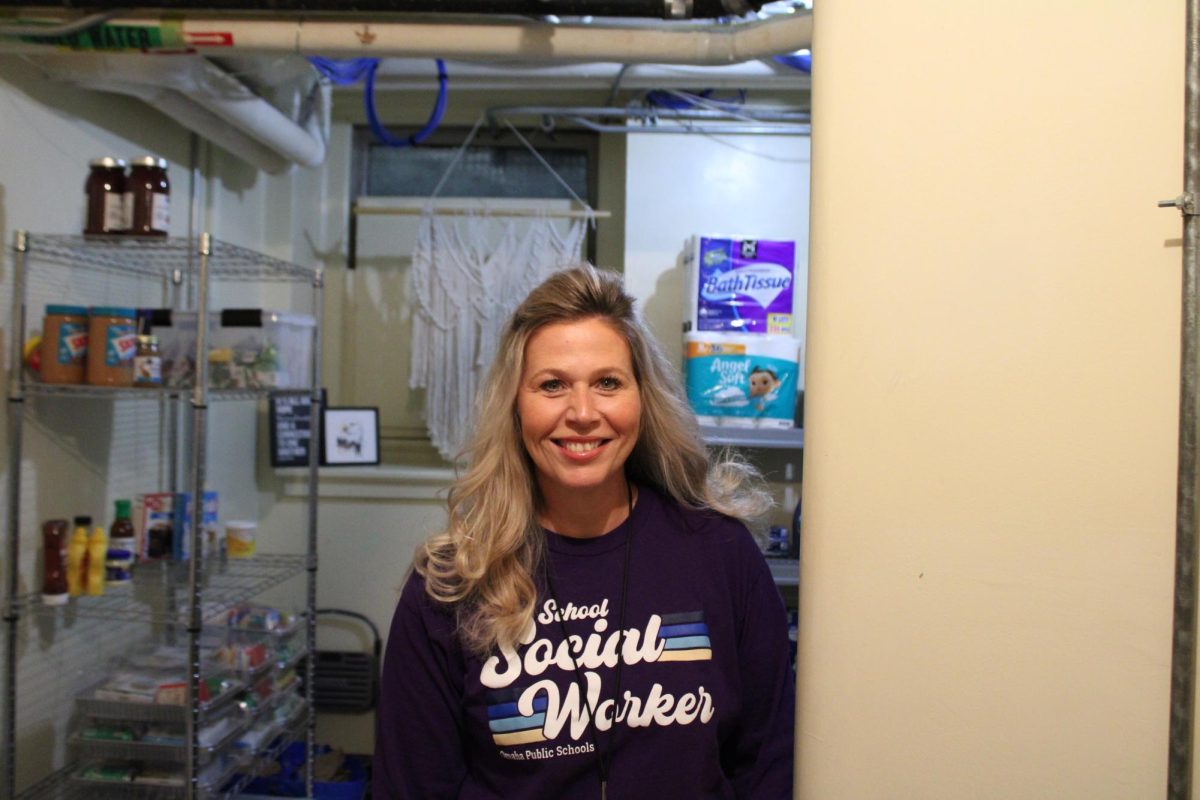 Mrs. Hill standing in front of food supplies and other essentials in the food pantry.