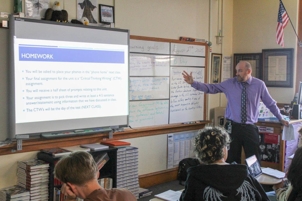 Government teacher Jordan Boyer, right, explains upcoming assignment plans to his students.