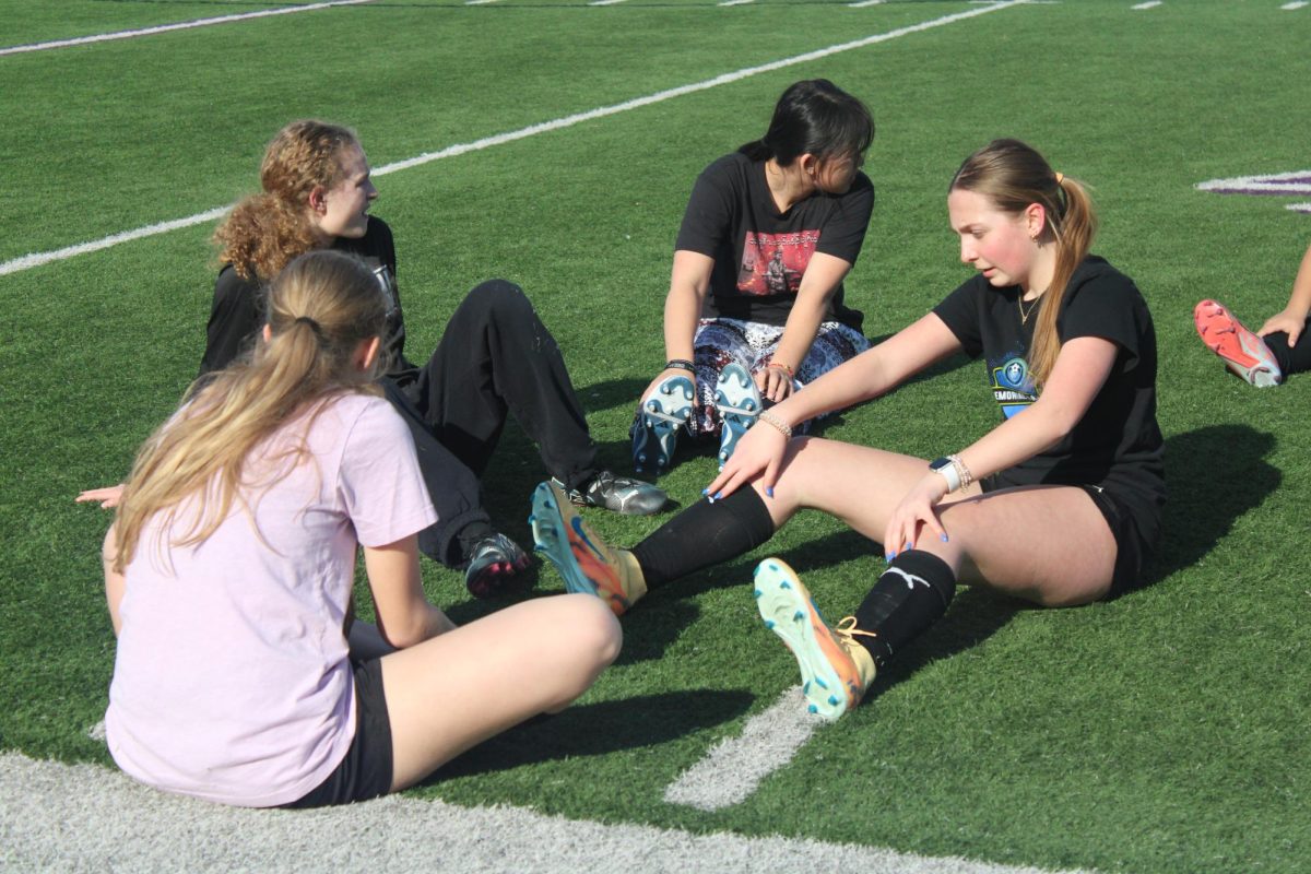 Sophomore Kirah Dunn stretching with a group of others on the side lines.