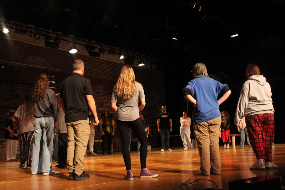 The group of drama kids taking improv instructions from the teacher